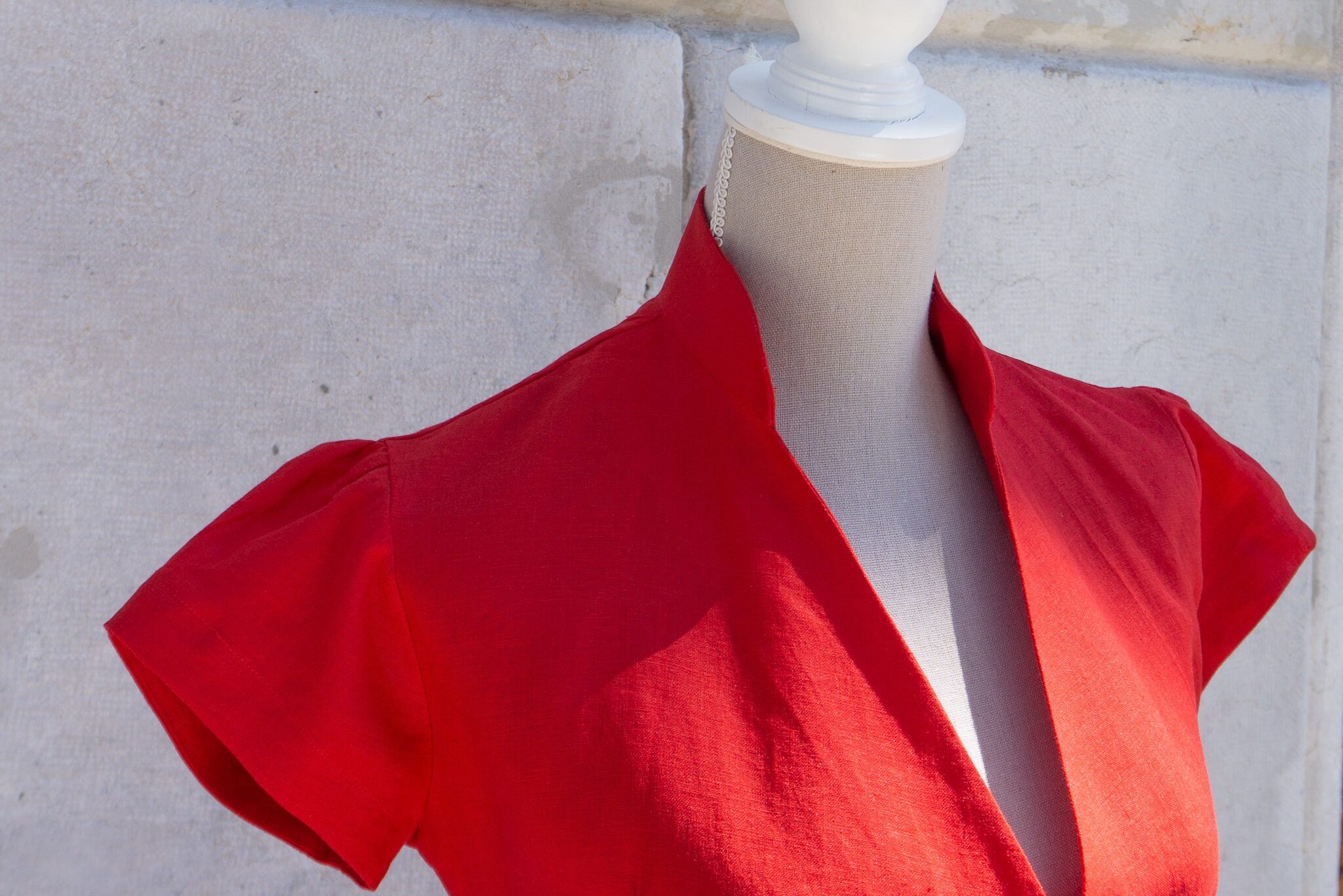 Robe chemise en lin rouge. Gros plan sur le col officier arrondi. Robe chemise sur mesure à manche courte. Une création Swiss Made de la Maison Revenga